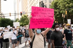 A protester marches through the street holding up a sign