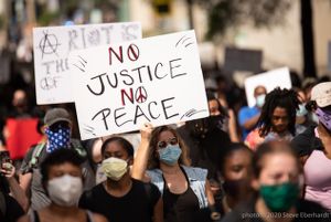 A protester holds up a sign reading 'No Justice, No Peace'