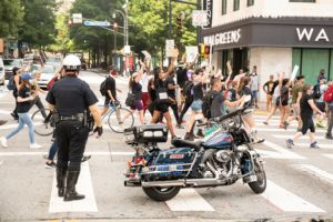 A police officer stands next to their motorcycle as they reroute protesters
