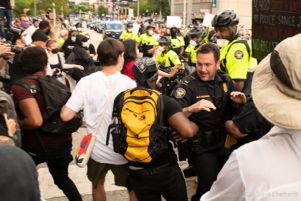 Police Officers begin to push protesters to the side of the street to let other officers through the crowd