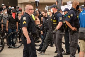 Officers walk an arrested protester down the street
