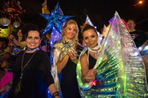 A group of women paraders stand with glowing paper lantern stars