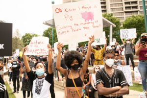 A protester holds up a sign reading 'Oh cause I thought a Pig Enabling the Murdering of Black People Said Some!!!'