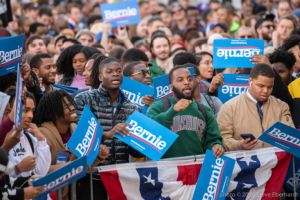 A large group of students all hold up 'Bernie' signs