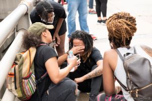 Protesters hold their hands over their eyes as others check on them and offer them water