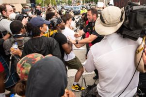 Police Officers begin to push protesters to the side of the street to let other officers through the crowd