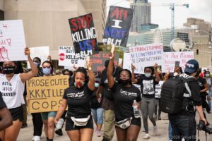 Protesters march through the street holding signs up in the air