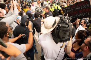 Police Officers begin to push protesters to the side of the street to let other officers through the crowd