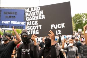 A protester holds up a sign reading 'Bland, Martin, Garner, Rice, Scott, King, Fuck 12'