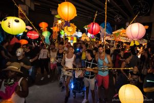 A crowd watches as paraders go by with paper lanterns