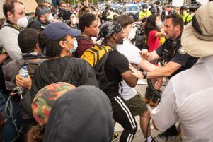 Police Officers begin to push protesters to the side of the street to let other officers through the crowd