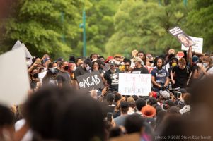 A woman speaks to the gathered crowd using a microphone