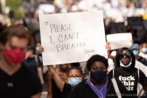 A protester holds up a sign reading 'Please. I Can't Breathe. -George Floyd'