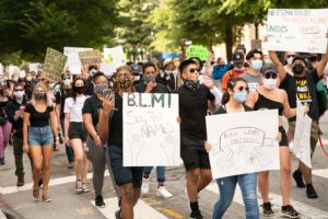Protesters march through the streets holding signs in the air as they march