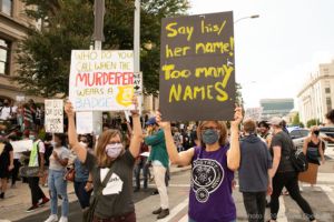 Two protesters hold up signs as they continue to march
