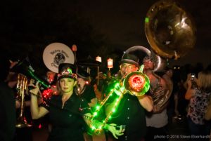 Two musicians march in the parade playing lit up instruments