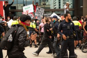 Officers walk an arrested protester down the street