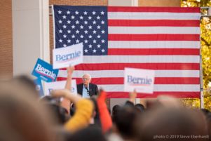 Bernie Sanders looks out at a crowd holding signs up in support