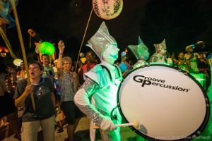 A group of drummers march followed by a group carrying more lanterns