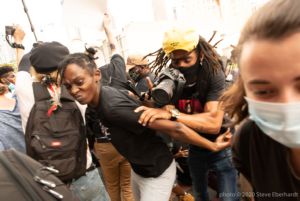 Protesters begin to push one another as they are moved off the streets by officers