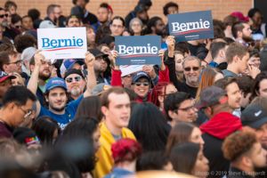 A group of supporters in the crowd all hold up 'Bernie' signs