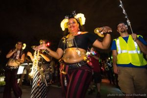 A woman with small cymbols walks through the parade