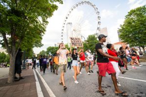 Protesters march down the street holding signs and shouting