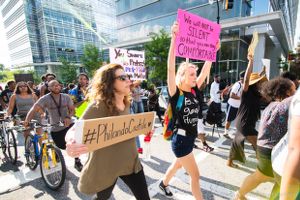 Protesters march by holding signs in the air