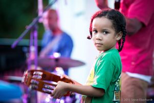 Child playing tambourine with Mausiki Scales & The Common Ground Collective; StillImage