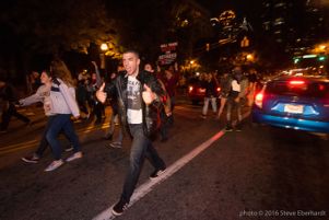 A protester marches through the streets holding up two thumbs up