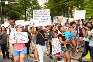 Protesters march down the street holding up various signs