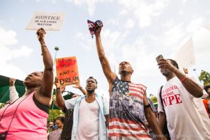 Protesters hold up their fists and signs in the air