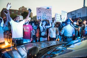 Protesters stand along the blockade line holds their hands and signs in the air