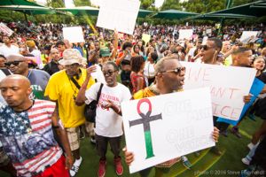 Protesters hold signs in the air as they gather at a rally to protest