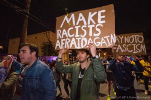 A protester marches holding a 'Make Racists Afraid Again' sign