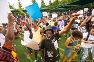 Protesters hold fists and signs in the air as they gather together