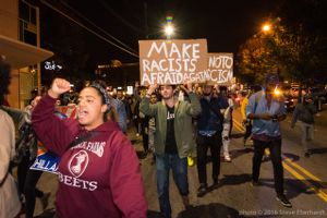 A protester marches holding a 'Make Racists Afraid Again' sign