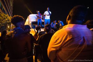 Protesters stand on top of a stuck semi-truck as they continue their protest