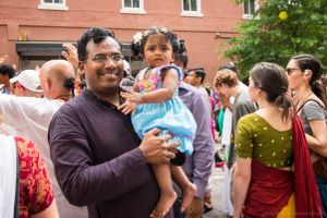 A father holds up his young daughter amongst the fesitval activities