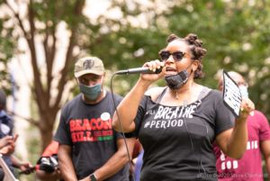 A female protester uses a microphone to speak to protesters