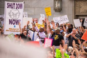 Reverand Raphael Warnock raises a hand in the air with fellow protesters while giving a speech