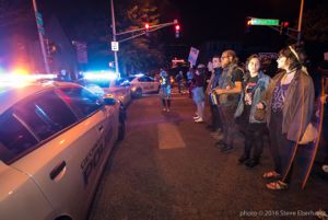 Protesters stand in a line as police cars pull up to their protest