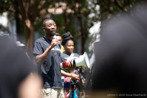 A protester uses a microphone to give a speech while holding a bullhorn