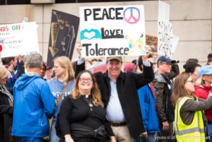 Protesters smile as they hold up a sign reading 'Peace, Love, Tolerance'