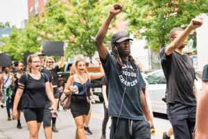 Protesters march by holding their fist high in the air