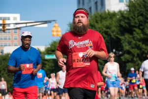 A man wearing a Braves shirt and headband jogs by in his race