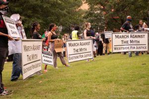 Protesters from multiple different parts of Atlanta gather in a circle holding up their banners