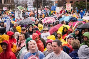 Protesters in ponchos and with umbrellas gather in the rain to protest