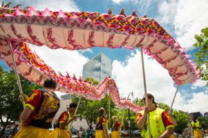 Festival Participants use sticks to walk a moving dragon through the parade