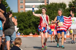 Mrs. Firecracker and the American Flag walk by the onlooking crowd waving